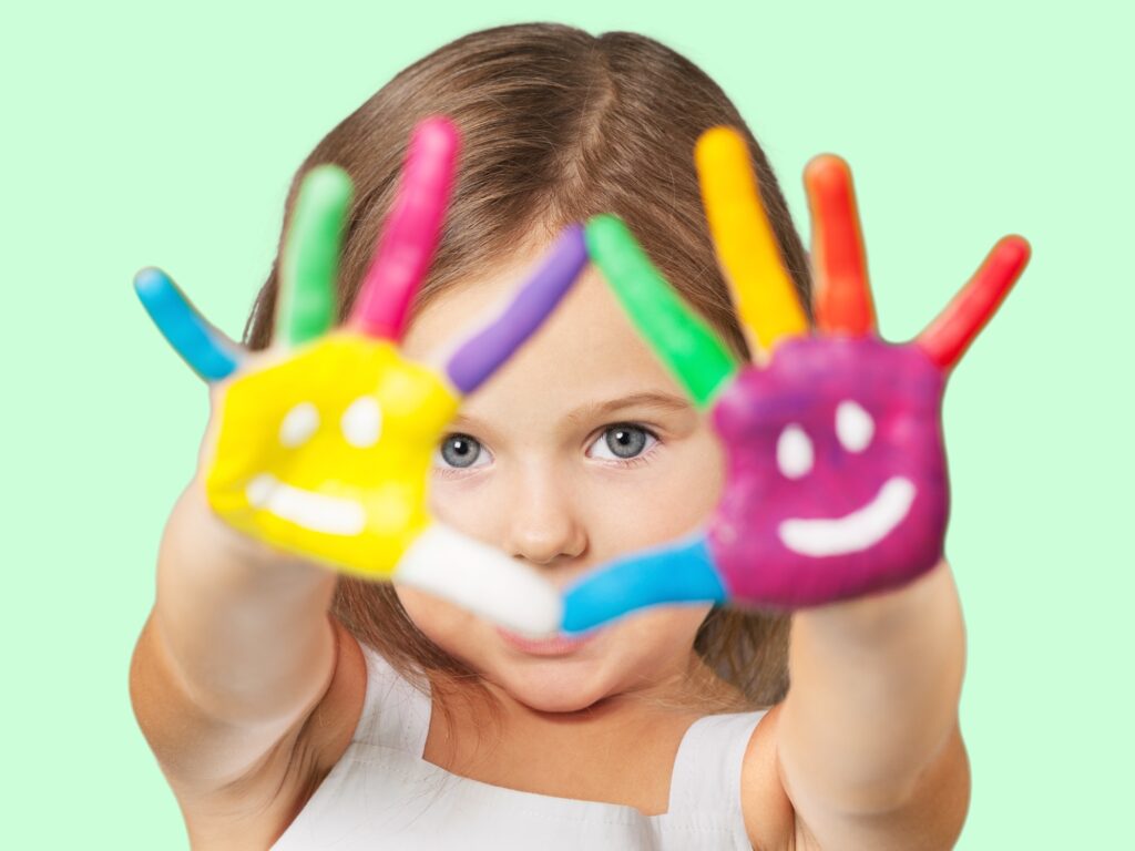 Girl with smiley faces painted with several colors on her palms - play-based learning - Kids Outside Adventures
